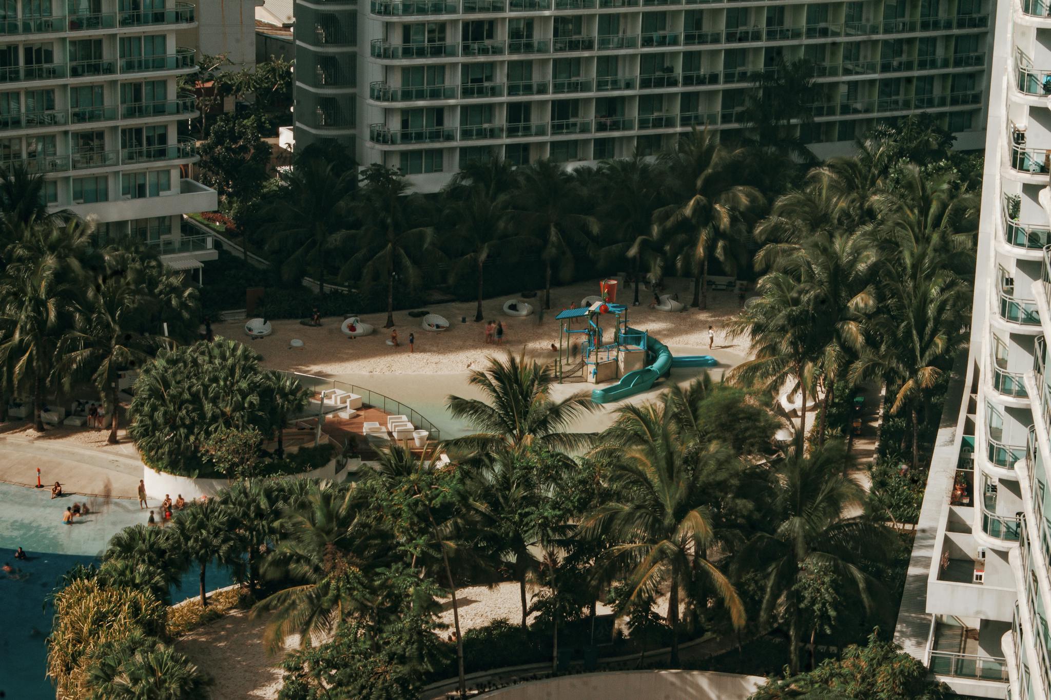 Aerial view of a luxury resort with swimming pool, palm trees, and leisure facilities, perfect for vacation and relaxation.