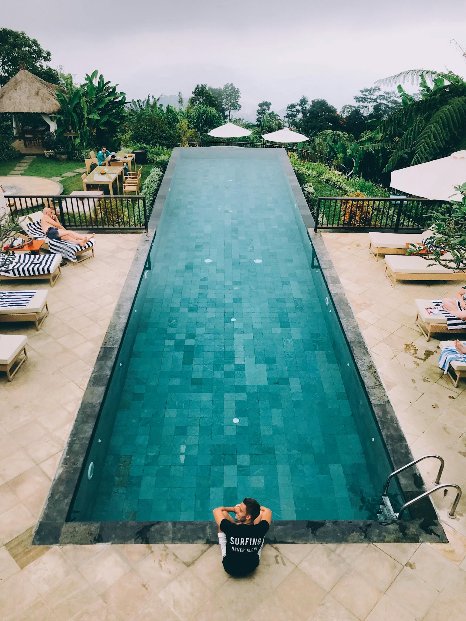 Relax in a serene infinity pool setting at a Bali resort surrounded by lush greenery.
